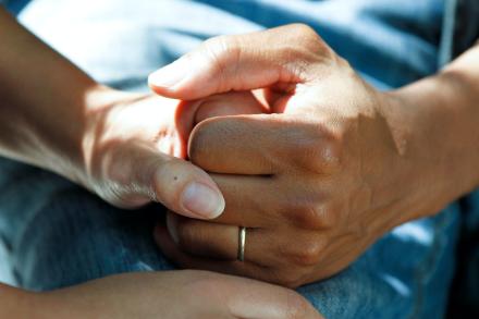 Dos personas tomándose de la mano de manera reconfortante.